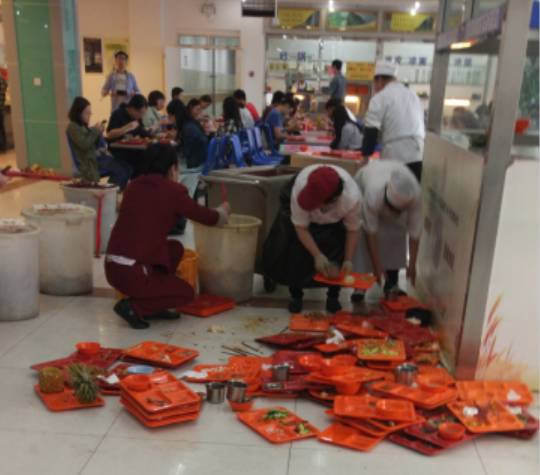 最忙碌的中午，收残区却只有一个人。阿姨一边收一边对学生说：“求求你们啦放地上吧，堆太多了会掉下来的……”